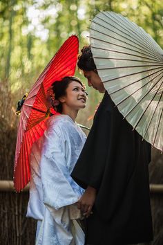 a man and woman dressed in traditional japanese garb holding an umbrella over their head