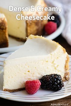 a slice of cheesecake on a plate with raspberries and blackberries next to it