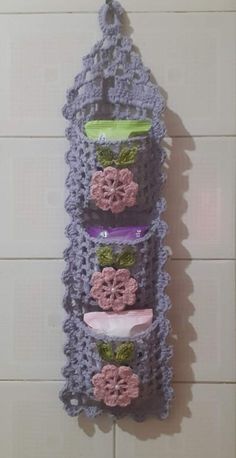 there is a crocheted wall hanging on the wall with soaps and toothbrushes in it