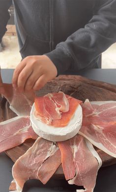 a person cutting meat on top of a wooden board