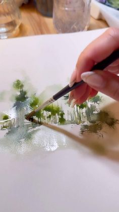 someone is painting trees with watercolors on paper