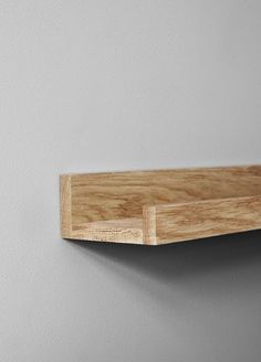 a wooden shelf mounted on the wall with a light gray wall in the back ground