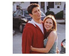 a young man and woman hugging in front of a car