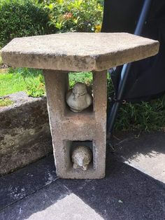 a stone bird bath with two birds in it's niche next to a lawn chair