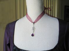 This choker/necklace has a gorgeous silver filigree pendant with a purple faceted teardrop glass stone. It hangs from a burgundy ribbon. The length is adjustable so it can be worn as a choker or necklace. It is reminiscent of 18th and 19th century jewelry designs. Comes in a lovely white gift box with ribbon. In the seventeenth and eighteenth centuries, chokers were very fashionable. Some were made of pearls, lace or ribbon and can be seen in many classic portraits. I think they're a very elegant accessory even today. 18th Century Necklace, 1780s Fashion, 18th Century Jewelry, Regency Jewelry, Burgundy Ribbon, Gift Box With Ribbon, Jewelry Victorian, Classic Portraits, Historical Jewellery