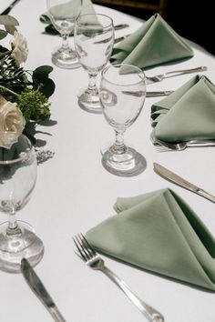 the table is set with silverware and green napkins