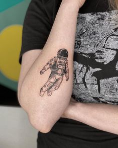 a woman with a small tattoo on her arm that shows an astronaut floating in space