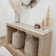 a wooden shelf with two baskets on it next to a mirror and christmas tree in the corner