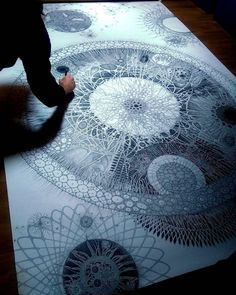 a person is drawing on a large piece of paper with black and white inks