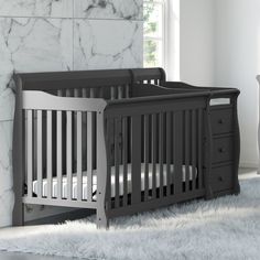 a baby crib sitting on top of a white rug next to a dresser and window