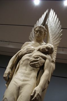 a statue of a man holding a baby in his arms with wings on it's back