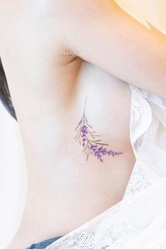 a woman's stomach with purple flowers on her side and the bottom part of her breast