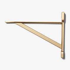 a gold metal shelf bracket on a white wall