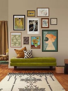 a green couch sitting in front of a wall filled with pictures and framed art on it