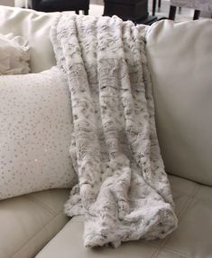 a white couch with pillows and a blanket on it