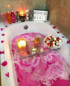 a bathtub filled with pink liquid and candles next to a sign that says morning world