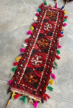 a red rug with colorful tassels on the floor