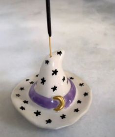 a white and purple hat with black stars on it, sitting on a saucer