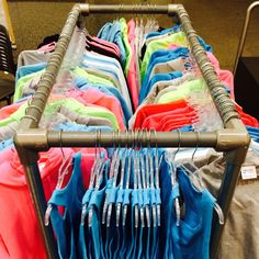 a rack filled with lots of different colored shirts next to each other on metal racks