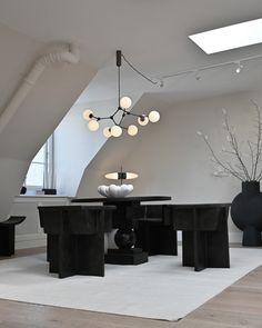 a modern dining room with black tables and chairs in the center, white rug on the floor