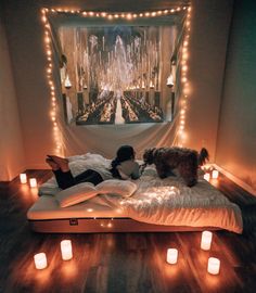 a woman laying on a bed with candles around her