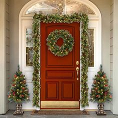 a red door decorated with christmas wreaths and lights