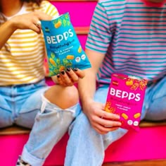 two people sitting on a bench holding bags of peeps