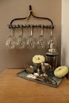 an assortment of wine glasses and silverware on a wooden table with a metal rack