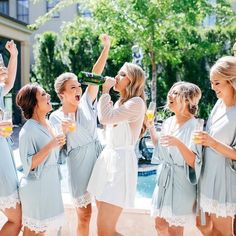 a group of women standing next to each other holding wine glasses in their hands and laughing