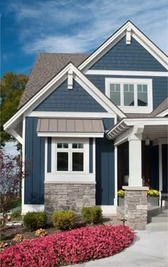 a house with blue siding and white trim on the front door, windows, and landscaping