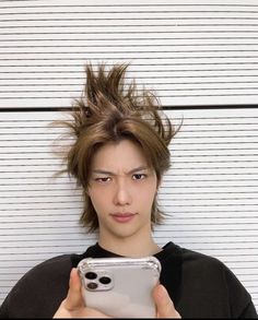 a young man holding a cell phone in front of his face and looking at the camera