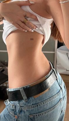 a woman in jeans and a white shirt is showing off her stomach with the number 11 on it