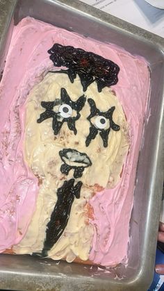 a cake decorated to look like a woman's face with black eyes and pink icing