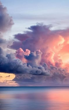 the sky is filled with pink and purple clouds over the ocean as the sun sets