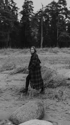 black and white photograph of a woman sitting on a rock in the middle of a field