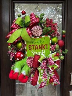 a christmas wreath on the front door with candy canes, ornaments and green letters