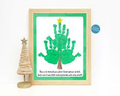 a green handprinted christmas tree next to a small pine tree with a star on top