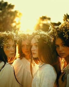 three women with flower crowns on their heads are posing for the camera while the sun is setting