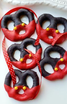 six decorated donuts on a plate with red and black ribbons tied around the doughnuts