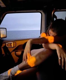 a woman sitting in the passenger seat of a vehicle with her hands on her knees