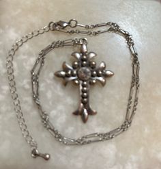 This is a silver-tone cross with a rhinestone in the center. There is no markings as to who made it. The unique-looking chain measures 15" long, plus it has a 3" extension chain. The cross measures 1 3/8" by 1 5/8". In excellent shape. The shipping weight will be 2 ounces. Metal Rhinestone Cross Pendant Necklace, Metal Cross Pendant Necklace With Rhinestones, Silver Cross Jewelry With Rhinestones, Silver Cross Metal Jewelry, Costume Jewelry Metal Cross Pendant, Costume Jewelry Cross In Metal, Metal Cross Necklace With Adjustable Chain, Adjustable Chain Metal Cross Necklace, Metal Cross Jewelry With Silver Chain