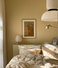 an unmade bed in a bedroom with two lamps on either side of the bed