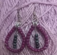 purple and black beaded hoop earrings on a pink yarn skeing with silver earwires