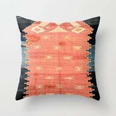 an orange, blue and black pillow on a white wall with the same color scheme