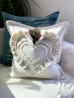 a white heart shaped pillow sitting on top of a bed