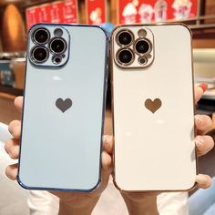 two people holding up cell phones with heart stickers on the back and front sides