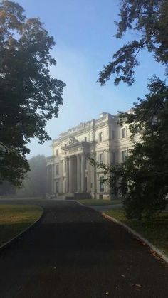 a large white building with columns on the front and side of it, surrounded by trees