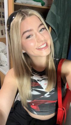 a woman with long blonde hair sitting in front of a book shelf and smiling at the camera