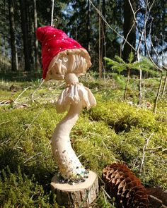 a mushroom statue is in the grass near pine cones