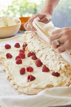 a woman is decorating a cake with raspberries on it